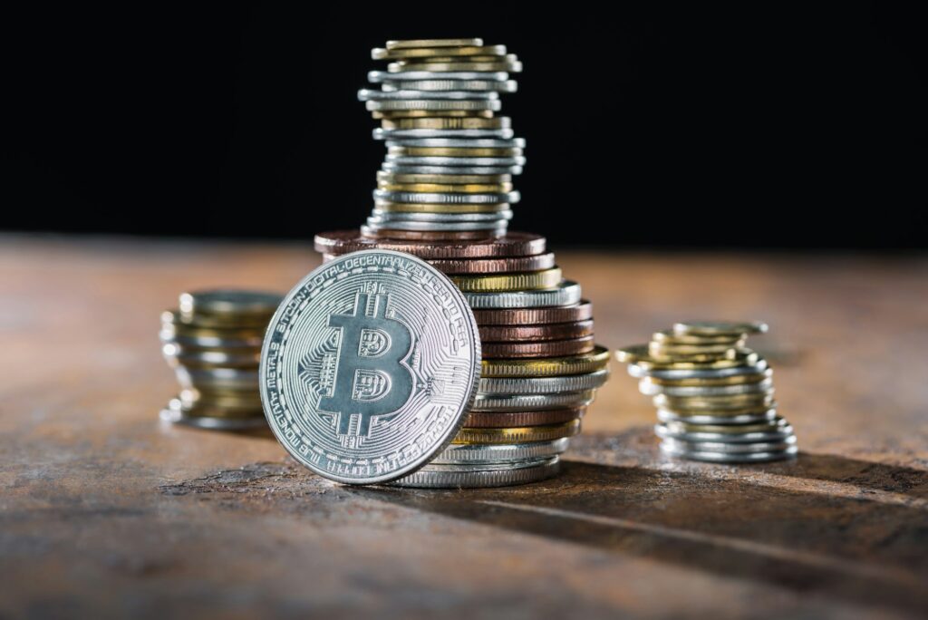 selective focus of silver bitcoin and piles of bitcoins behind